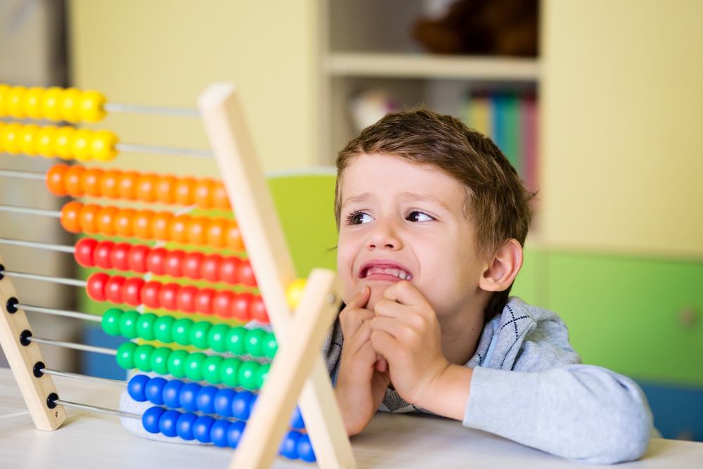 A cute Caucasian toddler boy having difficulties using the abacus